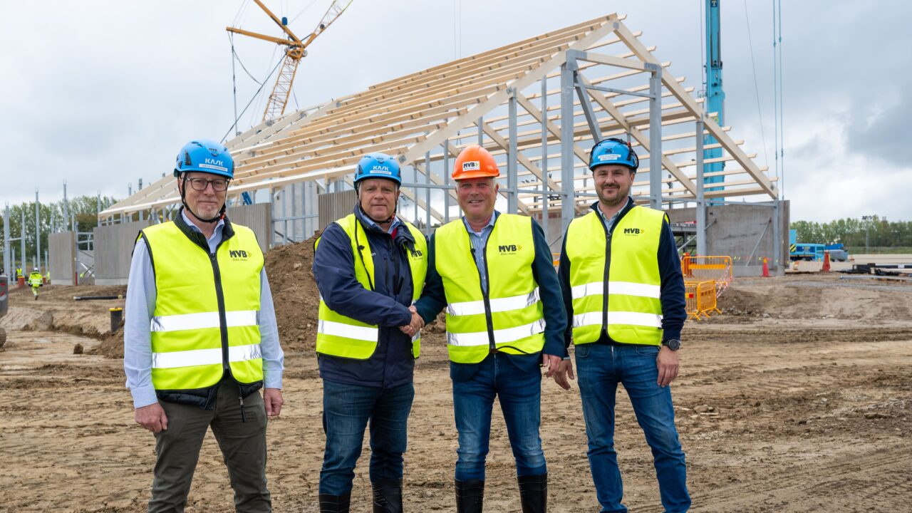 Fyra män i klädda i hjälm och varselväst framför byggnationen av Nya Jägersro Travarena